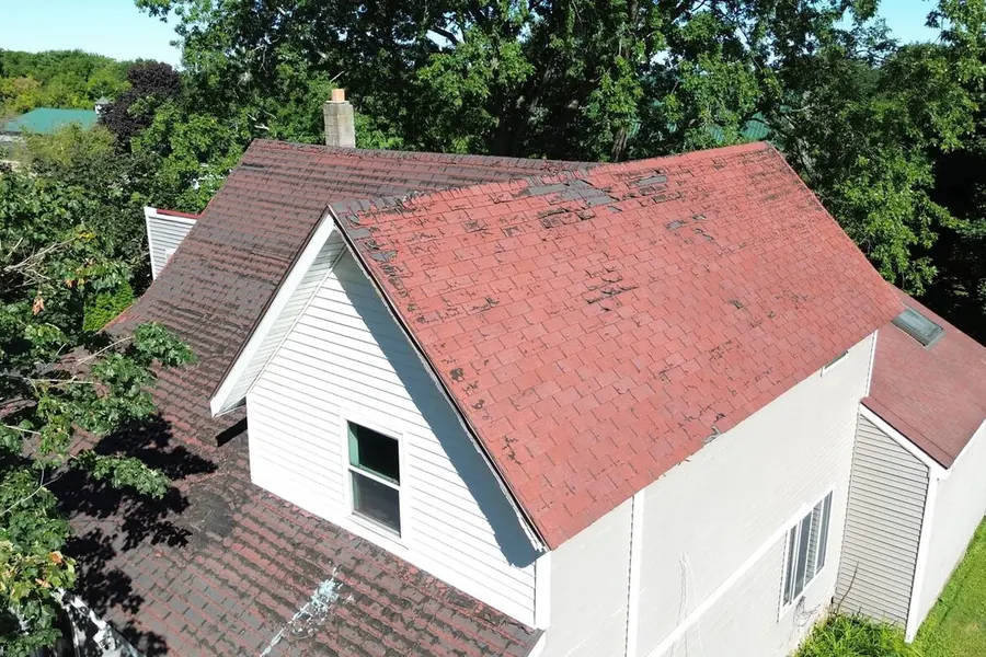 Weathered red roof on a white house photographed from the air