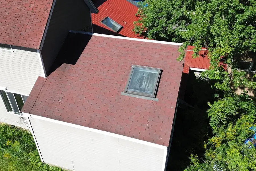 Close aerial detail of a dark red metal roof around a skylight