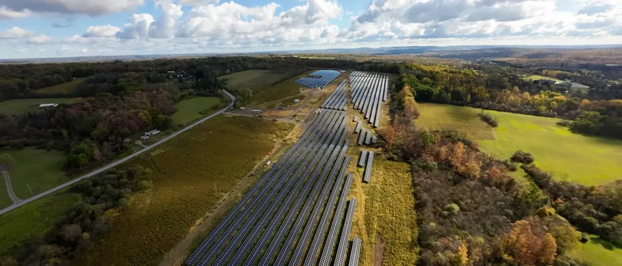 A solar array under construction, completed rows in the foreground and bare mounting frames beyond
